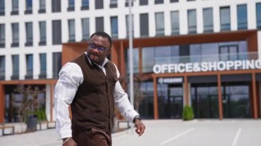 Çok ırklı ve tatmin olmuş genç bir iş adamı başını çevirip dikkatle bir şeye bakıyor. Beyaz tişörtlü şık bir adam iş yerine yürüyor. Başarı, insanlar ve iş kavramı