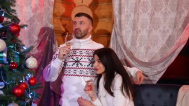 Noel ağacının yanında şampanya içen romantik bir çift. Mutlu koca ve güzel eş yeni yılı evde alkol içerek kutluyor.