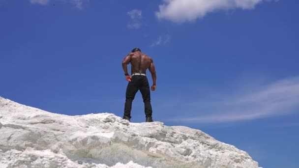 强壮的运动健美模特 一个全身赤裸的男人的低角度照片显示了六块腹肌 背景上蓝蓝的天空 — 图库视频影像