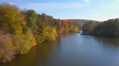 Hava görüntüsü. Güneşli ormanların ve geniş nehirlerin üzerinde uçuyor. Sonbahar ormanı ve manzara konsepti