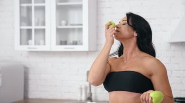 Sağlıklı elmalarla masanın yanında duran ve onunla oynayan güzel esmer beyaz kadın. Sağlıklı beslenme konsepti