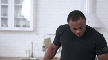 Modern iç mekanda meyve ve sebzelerle dolu mutfakta duran ve tablete bakan çok kültürlü bir adam. Gıda ve sağlık hizmeti kavramı