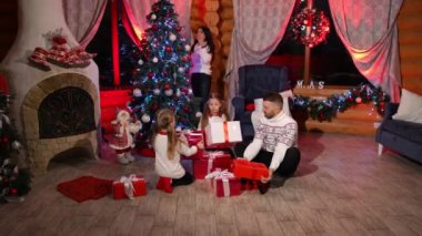 Mutlu aile Noel hediyelerini açıyor. Babaları ve küçük kızları yakın yıl arifesinde birlikte oturup hediye kutularına bakıyorlar. Annem Noel ağacının yanında dekore ediyor. Evde şenlik havası var.