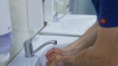 Klinikte elini yıkayan bir doktor. Ameliyattan önce ellerini yıkayan cerrahı kapat.