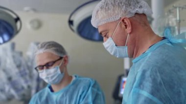Mikroskoplu beyin cerrahları. Mavi üniformalı profesyonel doktorların ekip çalışması modern tıbbi ekipmanlarla bir nörocerrahi yürütüyor.
