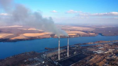 Açık gökyüzü arka planında duman boruları. Fabrika bacaları atmosfere karanlık emisyonlar salar. Kimyasal duman havayı kirletir. Ekoloji tehlikede