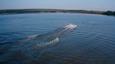 Gün batımında su yüzeyinde tekne. İnsanlar güzel su arka planında akşam nehri boyunca sürat teknesini sürüyorlar. Hava görünümü