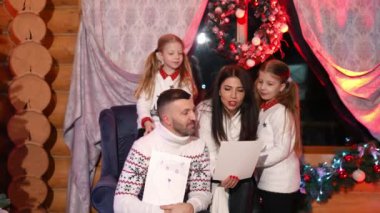 Şuna bir bak. Küçük kızlar evde aileleriyle vakit geçirirken el yapımı resimlerini gösteriyorlar. Çocuklar Noel Baba 'yı bekliyor.