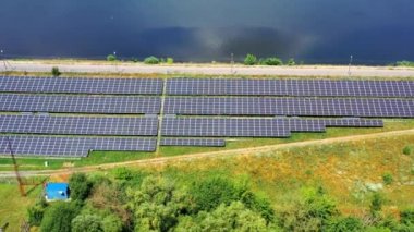 Sahadaki uzun güneş panellerinin üzerinden uçmak. Güneşli bir günde yol kenarında fotovoltaik güneş pilleri. Alternatif yeşil enerji. Hava görünümü