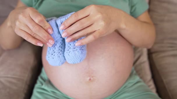 Έγκυος Καυκάσιος Γυναίκα Κάθεται Στο Κρεβάτι Της Μερικά Πλεκτά Μποτάκια — Αρχείο Βίντεο