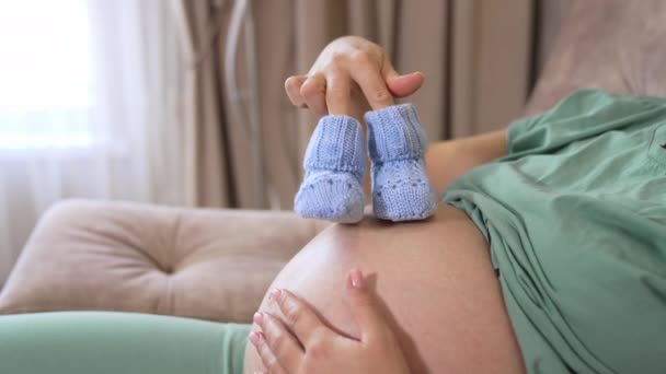 快乐地等待着坐在床上享受母性的高加索女人 复制空间 在家里带着婴儿靴的年轻孕妇 — 图库视频影像