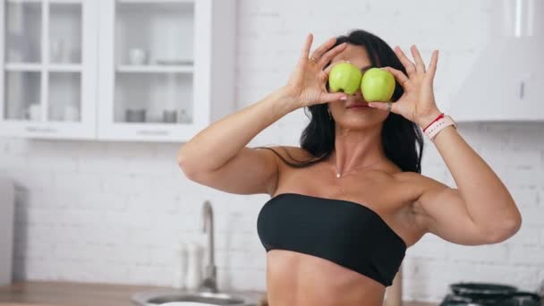 台所の女性は野菜や果物と食事を準備する準備ができている 女性はリンゴを目の近くに持っている 台所の背景 健康食品 ベジタリアン ヴィーガン — ストック動画