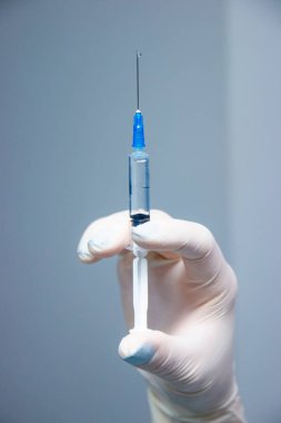 Dişçi elinde beyaz eldivenli küçük bir Syquet tutuyor. Karın ağrısı ve diş tedavisi fotoğrafı. Beyaz eldiven takan bir dişçi, diş tedavisinde kullanılan küçük bir şırınga tutar..