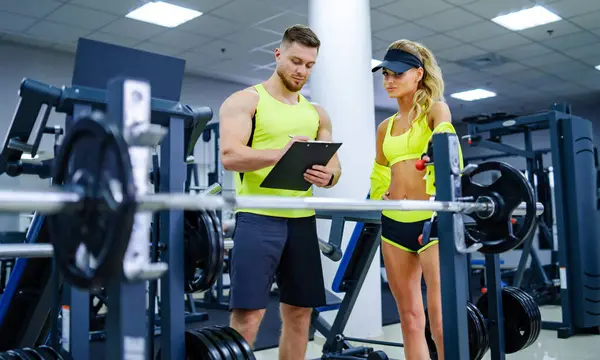Fitness training couple in gym. Attractive trainer body working out.