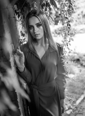 Siyah ve Beyaz Fotoğrafta Ağaca Yaslanan Kadın. Siyah beyaz bir kadın resmi, bir ağaca yaslanmış..