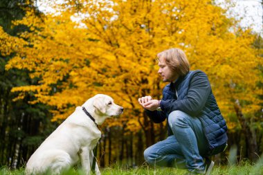 Açık havada Beyaz Köpek 'in yanında diz çöken adam.