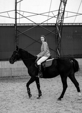 Siyah Atın Arkasında Binen Kadın. Bir kadın, görkemli siyah bir atın sırtında güvenle ata biner..