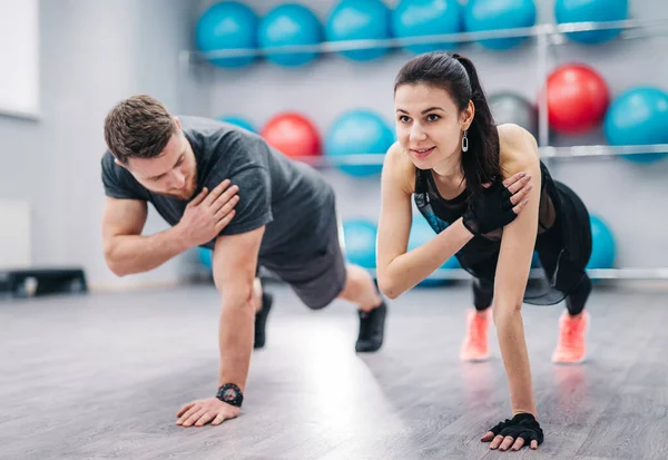 A Man and Woman Doing Push Ups in a Gym. A man and woman are positioned on the gym floor, performing push ups with precision and strength.