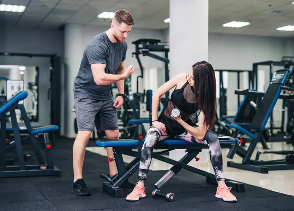 Man and Woman Standing Together in a Gym. A man and a woman stand side by side in a gym.