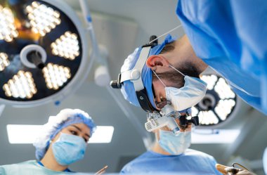 Cerrahlar ameliyathanede ameliyat ediyorlar.