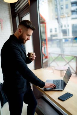 Adam kafede dizüstü bilgisayarda çalışıyor..