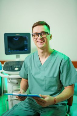 Yeşil üniformalı gülümseyen erkek dişçinin portresi.