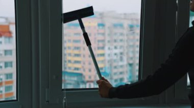 Su ve aletlerle cam temizliği. Cam temizleyicisi ıslak pencerelerle çalışıyor.