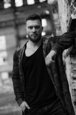 Siyah beyaz fotoğrafta adam duvara yaslanıyor..