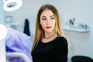 Güzeller güzeli genç bir kadın güzellik salonunda aynanın karşısında oturuyor.