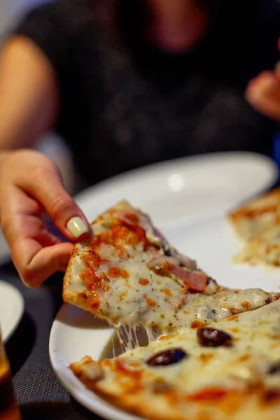 Woman is eating slice of pizza in restaurant