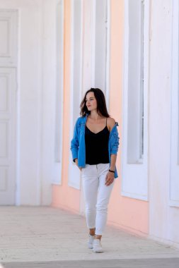 Mavi ceketli, beyaz pantolonlu güzel bir kadın etrafta dolaşıyor.