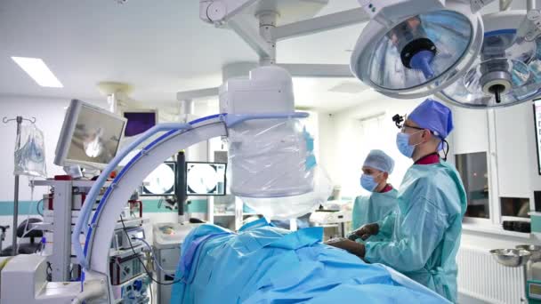 Dwóch Chirurgów Przeprowadza Operację Patrzy Ekran Dobrze Wyposażona Sala Operacyjna — Wideo stockowe