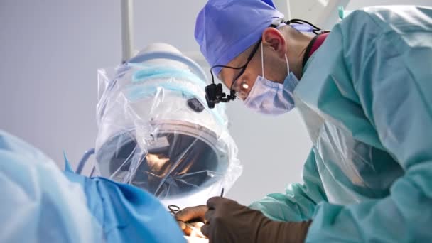 수술을 수행하기 구부러진 외과의를 의사는 양손에 악기를 환자에게 적용합니다 아래에서 — 비디오
