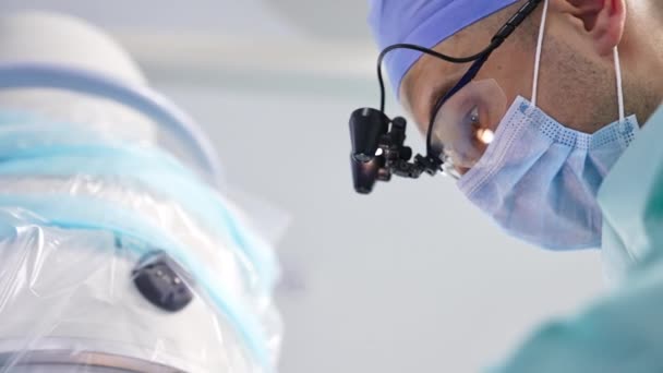 特殊装置を備えたマスク メガネの薬は手術室で作動する 手術中の医師の肖像画 クローズアップ バックグラウンド — ストック動画