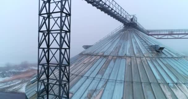 上升到巨大的粮仓顶部 金属上的鸟支撑在电梯水箱上 背景是冬季雾蒙蒙的风景 — 图库视频影像