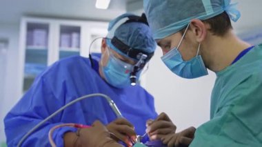 Hastanın burnundan ameliyat yapan iki doktor. Cerrah ekibi ameliyat sırasında tıbbi aletlerle ilgileniyor. Bulanık arkaplan.