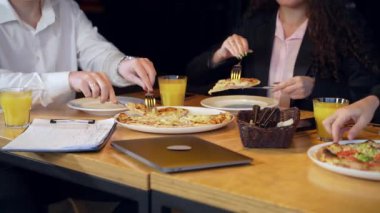 İş adamları öğle arasında pizza yiyorlar. İş arkadaşları yemek yiyor ve iş konularını tartışıyor..