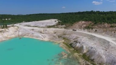 Açık çukur madenciliğinin muhteşem manzarası. Yığınla killi kamyon tepe boyunca gidiyor. Yeşil orman arkaplanı.