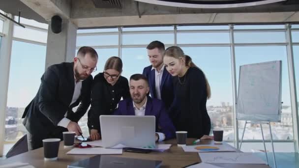 商业团队站在首席执行官身边 看着笔记本电脑 其中一个男同事展示了他的智能手机 — 图库视频影像