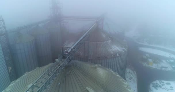 近代的な農業プラントの穀物エレベーターのほこりのトップ 霧の冬の日に強力なサイロ複合体の上を飛行する エアリアルビュー — ストック動画