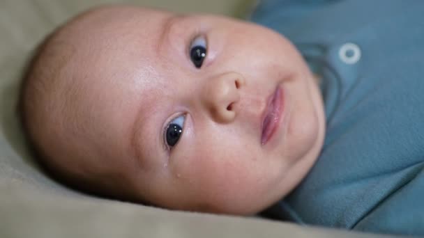 バラ色の頬をした素敵な赤ちゃんの顔 頭に横たわっているかわいい赤ん坊の少年は カメラの前で甘やかしに振り向いた クローズアップ — ストック動画