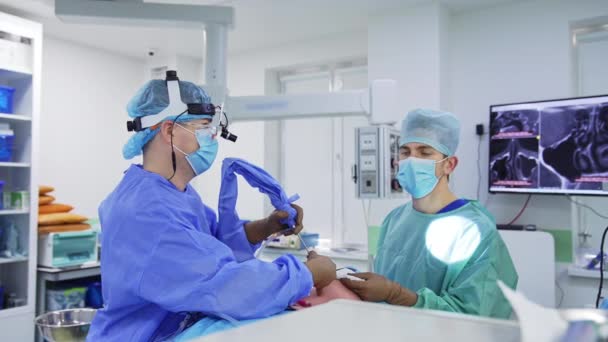 現代の診療所における外科手術 スクリーンのプロセスを監視する外科医 医師を支援する男性看護師 — ストック動画