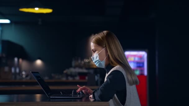 ノートパソコンを使った若い女性社員 オフィスで働いている間 マスクを着ている女性 サイドビュー バックグラウンド — ストック動画