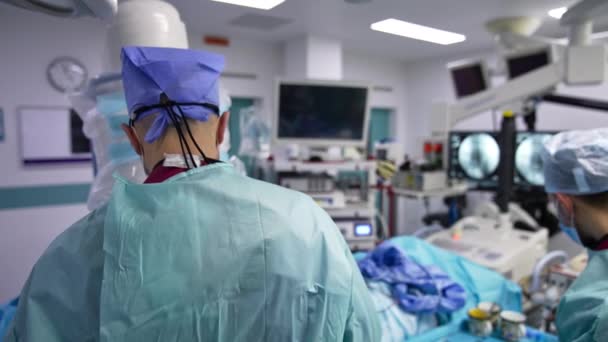 Pria Ahli Bedah Berdiri Dengan Punggung Kamera Dan Melakukan Operasi — Stok Video