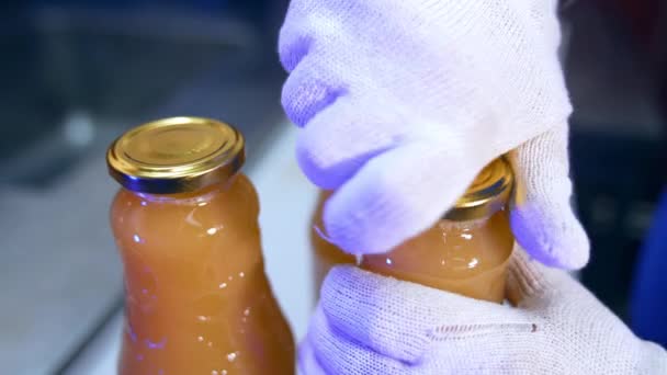手袋の食品工場労働者の手は ボトルにキャップを置きました 閉じている瓶の新鮮なりんごジュース — ストック動画