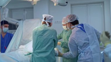 Operasyon masasında büyük bir cerrah ekibi var. Travma ameliyatıyla ilgilenen üç profesyonel erkek doktor..