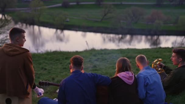 Grupa Młodych Ludzi Siedzących Trawie Słyszy Ognisko Śpiewa Piosenki Przyjaciele — Wideo stockowe