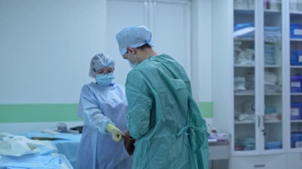Genç Erkek Cerrah Ameliyata Hazırlanıyor Kadın Asistan Doktorun Lateks Eldiven — Stok video