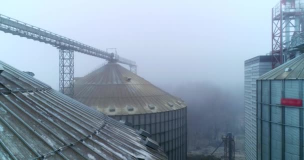 エレベーターの汚れた屋根は 天候が悪かった 農業プラントの金属タンクの間を高く飛んでいる ドローンの映像 — ストック動画