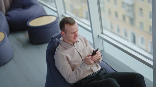 Joven Sosteniendo Teléfono Enviándole Mensajes Alguien Empleado Masculino Sentado Cómodo — Vídeo de stock